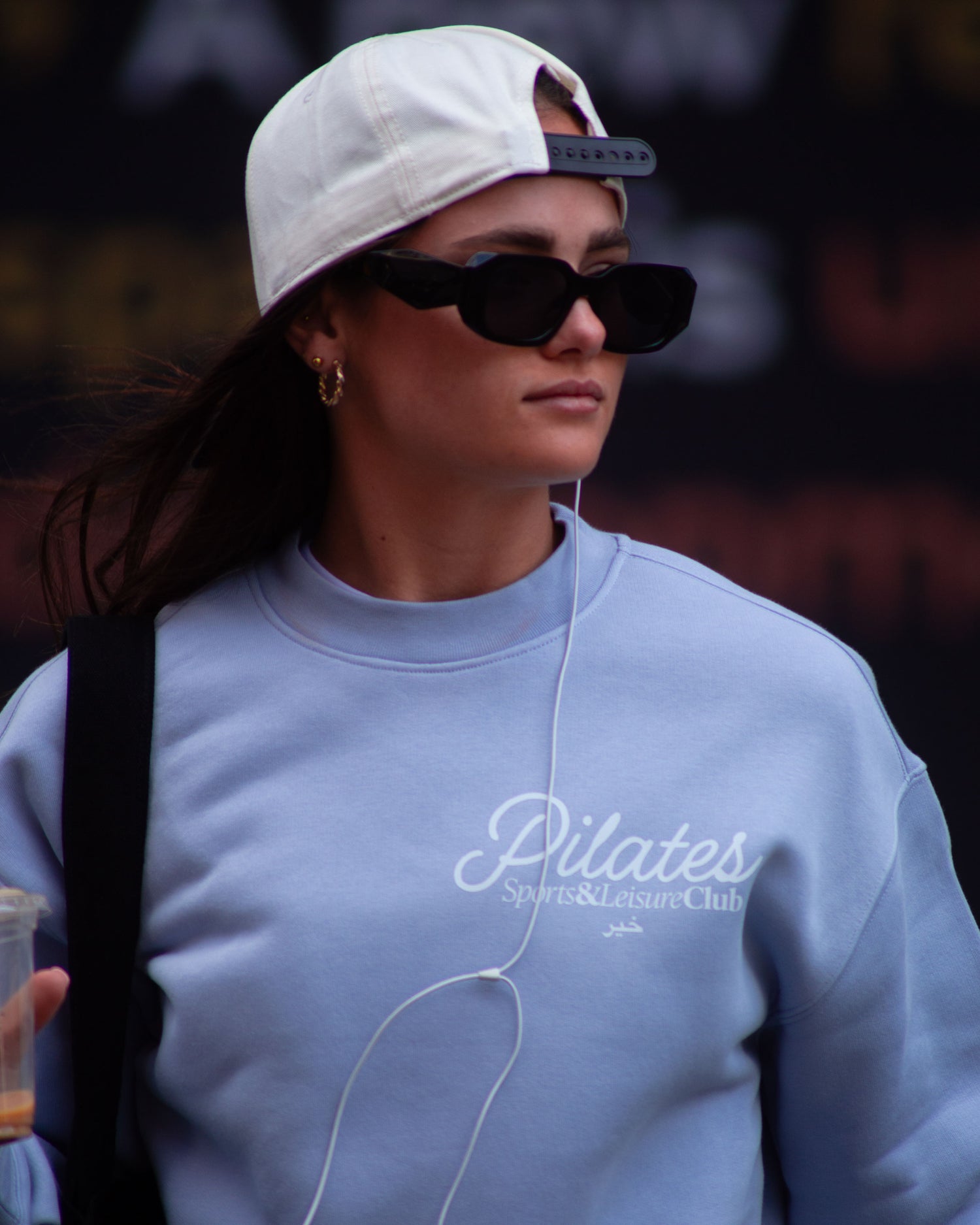 Woman wearing powder blue Pilates Sports & Leisure Club oversized crewneck sweatshirt, streetwear lifestyle photo.